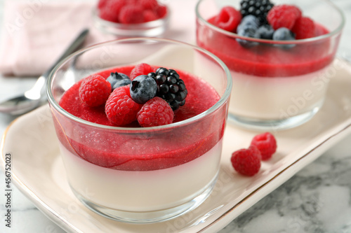 Fotografija Delicious panna cotta with fruit coulis and fresh berries served on white marble