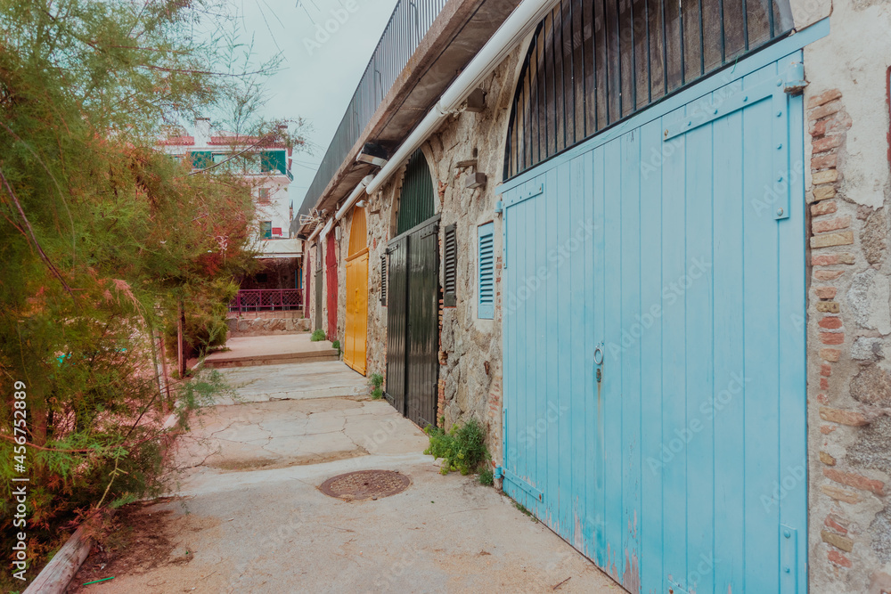 Ancient light blue wooden door on a stone wall with more colorful doors at the bottom in Calella de Palafrugell village Ancient light blue wooden door on a stone wall with more colorful doors at the bottom in Calella de Palafrugell village