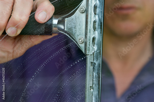 Caucasian man using a squeegee to clean a window