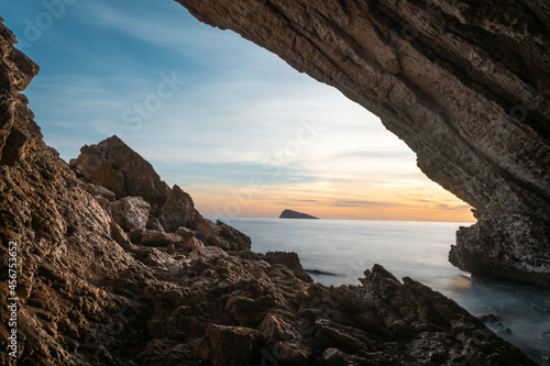 Cueva en el mar de Benidorm con vistas a una isla en la hora del atardecer.