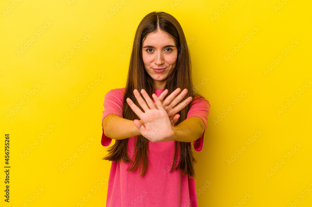 Young caucasian woman isolated on yellow background standing with outstretched hand showing stop sign, preventing you. Young caucasian woman isolated on yellow background standing with outstretched hand showing stop sign, preventing you.