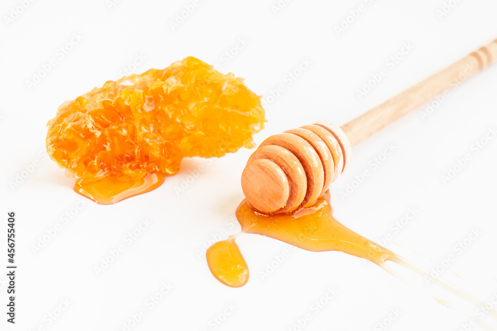 Honey wooden spoon with piece of honeycomb on white background. Organic fresh liquid honey. Healthy food Honey wooden spoon with piece of honeycomb on white background. Organic fresh liquid honey. Healthy food