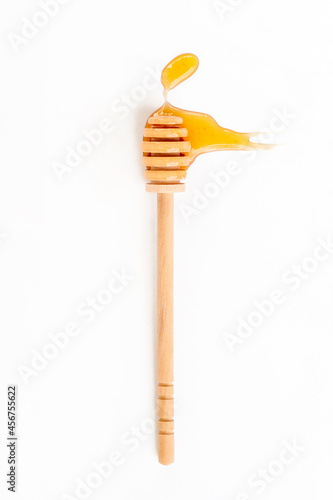 Drops of honey and honey wooden spoon on white background, top view