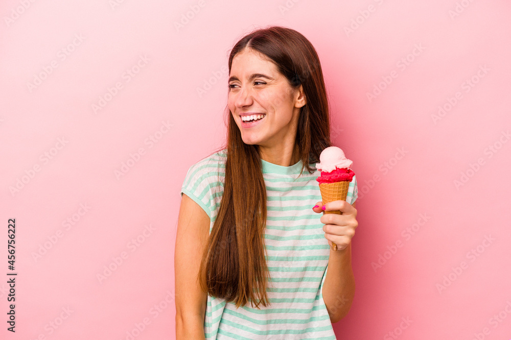 Young caucasian woman holding an ice cream isolated on pink background looks aside smiling, cheerful and pleasant. Young caucasian woman holding an ice cream isolated on pink background looks aside smiling, cheerful and pleasant.