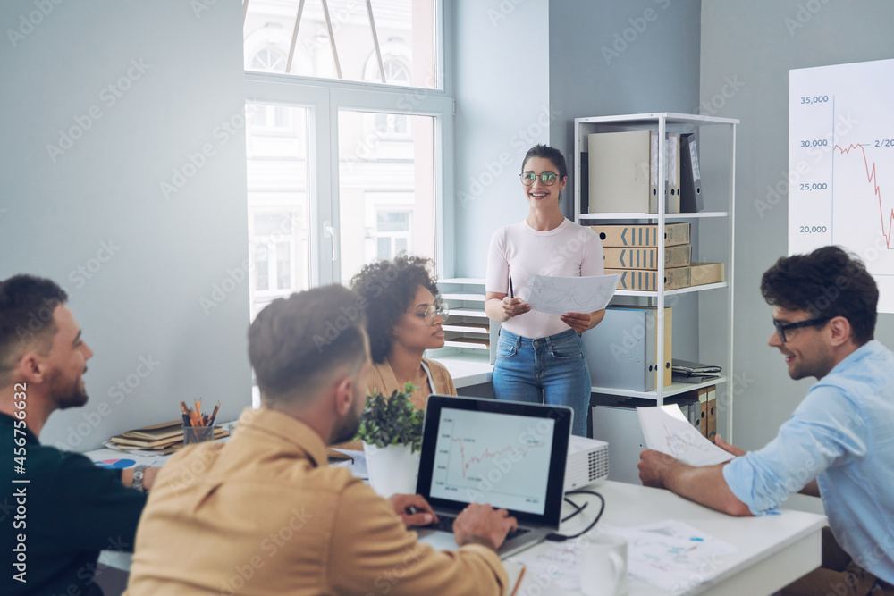 Obraz premium Group of young modern people in smart casual wear discussing business while having meeting in office