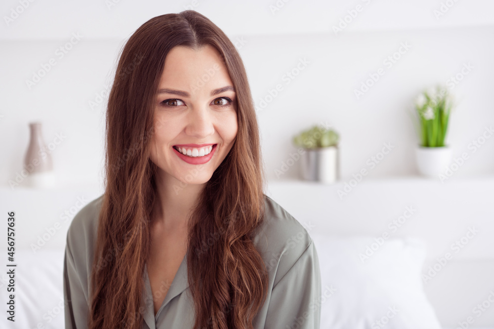 Portrait of attractive cheerful girl sitting on bed spending weekend awakening at home house light white interior Portrait of attractive cheerful girl sitting on bed spending weekend awakening at home house light white interior