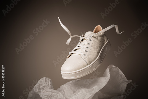 Fotótapéta Fashion - white leather unisex sneakers shoe levitating on the gray background