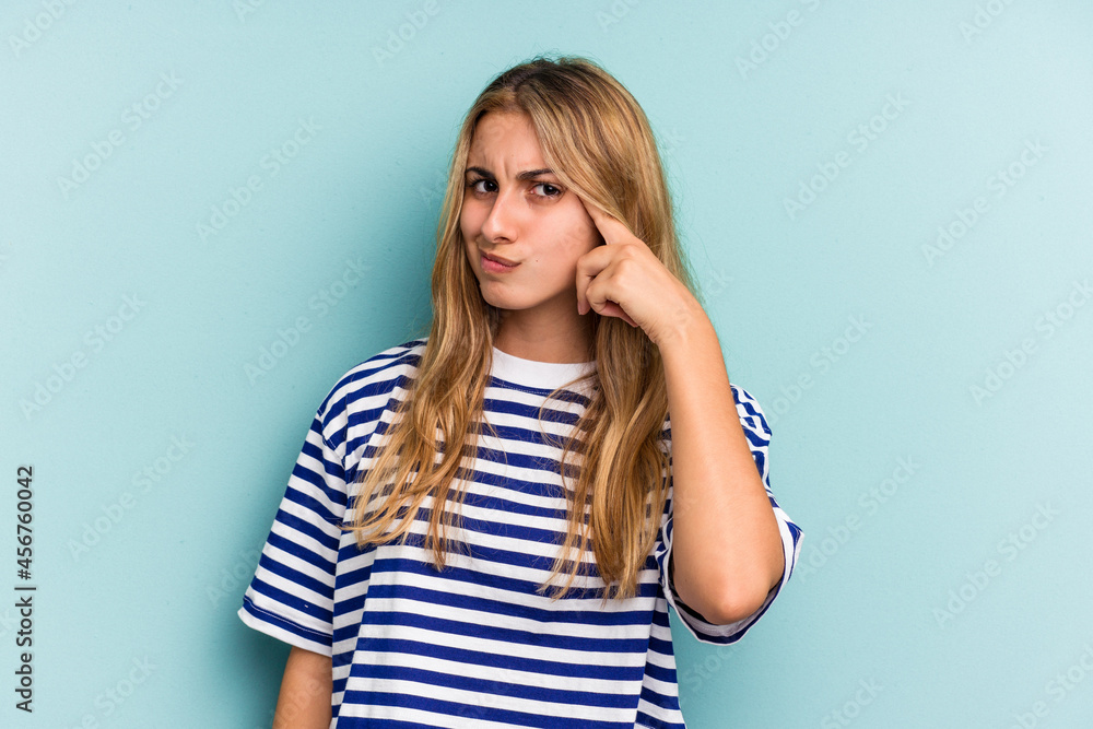 Young caucasian blonde woman isolated on blue background pointing temple with finger, thinking, focused on a task. Young caucasian blonde woman isolated on blue background pointing temple with finger, thinking, focused on a task.