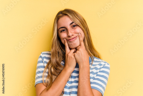 Young caucasian blonde woman isolated on yellow background doubting between two options.