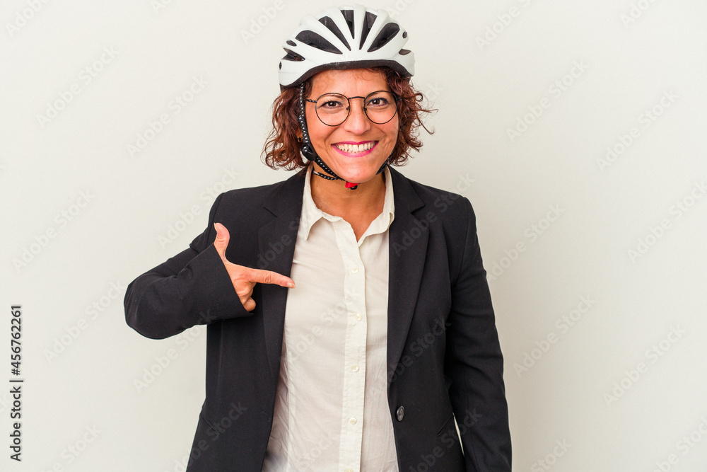 Middle age latin business woman wearing a bike helmet isolated on white background person pointing by hand to a shirt copy space, proud and confident Middle age latin business woman wearing a bike helmet isolated on white background person pointing by hand to a shirt copy space, proud and confident