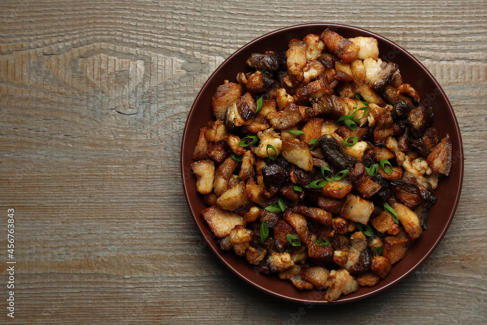 Tasty fried cracklings on wooden table, top view with space for text. Cooked pork lard Tasty fried cracklings on wooden table, top view with space for text. Cooked pork lard