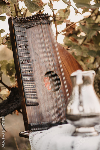 фотографія Vertical closeup of a brown zither on the table outdoors.