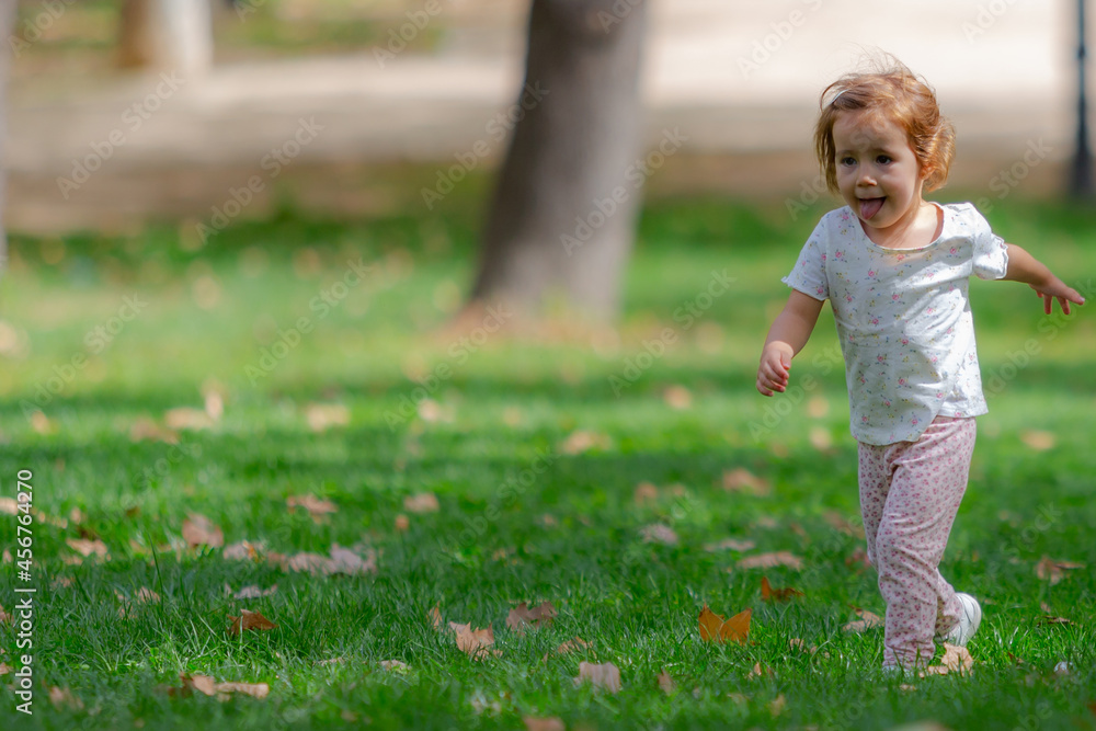 Little girl running and playing on the grass in the park. Kids outdoors Little girl running and playing on the grass in the park. Kids outdoors