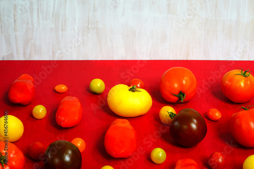 Colorful yellow and red heirloom tomatoes arranged on a red background © eqroy