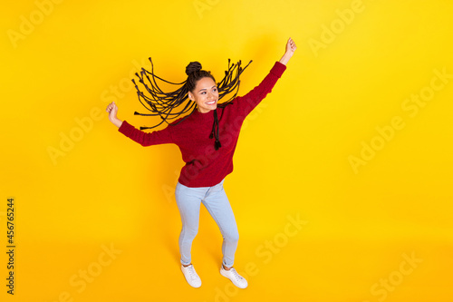 Full length photo of cute pretty dark skin woman dressed red sweater dancing smiling isolated yellow color background