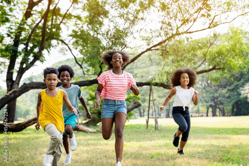 Group of cheerful kids running in the park in summer.