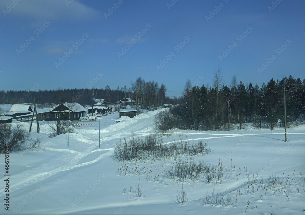 Winter rural landscape. Beautiful view with village houses, snow and trees on a sunny winter day in the countryside in Russia.