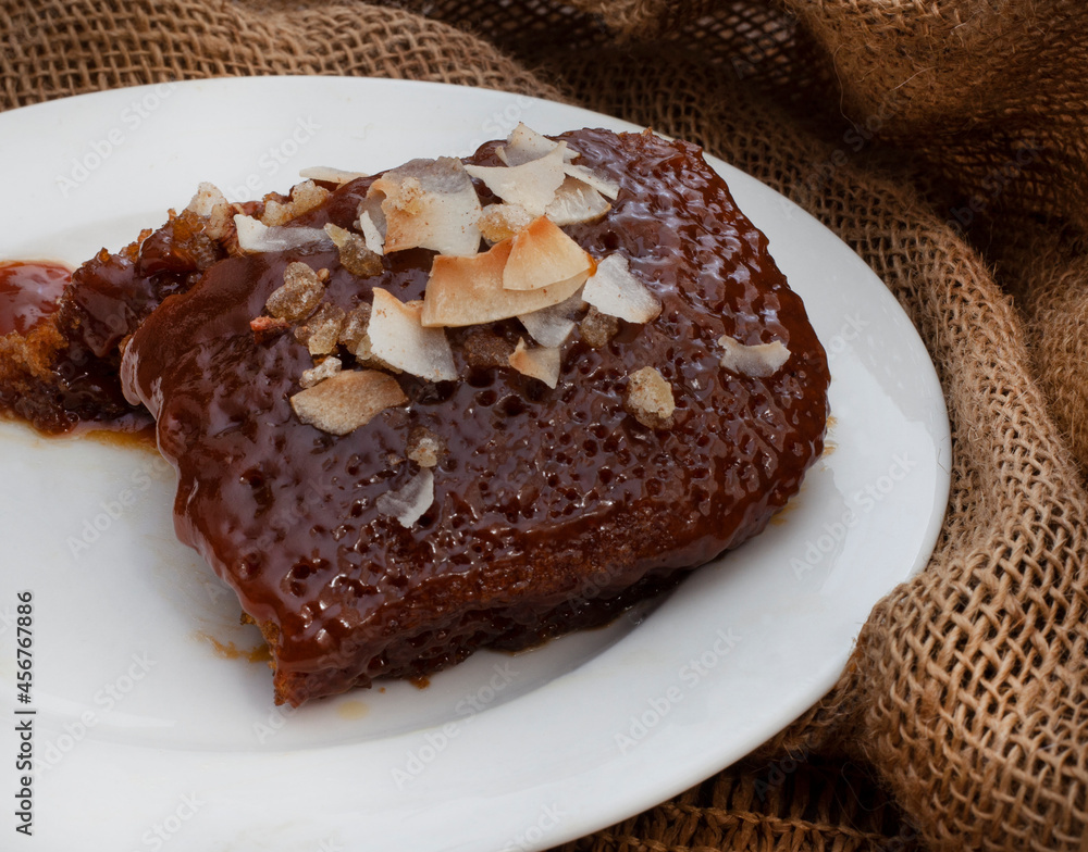 Ginger and Caramel warm pudding with roasted coconut sprinkle. serving on white plate on burlap or hessian cloth for a warm rustic feel Ginger and Caramel warm pudding with roasted coconut sprinkle. serving on white plate on burlap or hessian cloth for a warm rustic feel