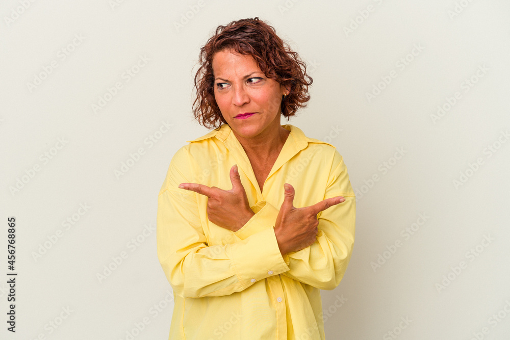 Middle age latin woman isolated on white background points sideways, is trying to choose between two options. Middle age latin woman isolated on white background points sideways, is trying to choose between two options.