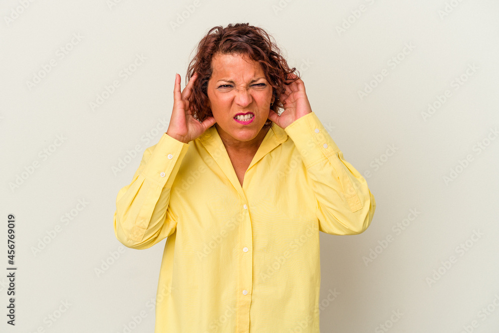 Middle age latin woman isolated on white background covering ears with fingers, stressed and desperate by a loudly ambient. Middle age latin woman isolated on white background covering ears with fingers, stressed and desperate by a loudly ambient.