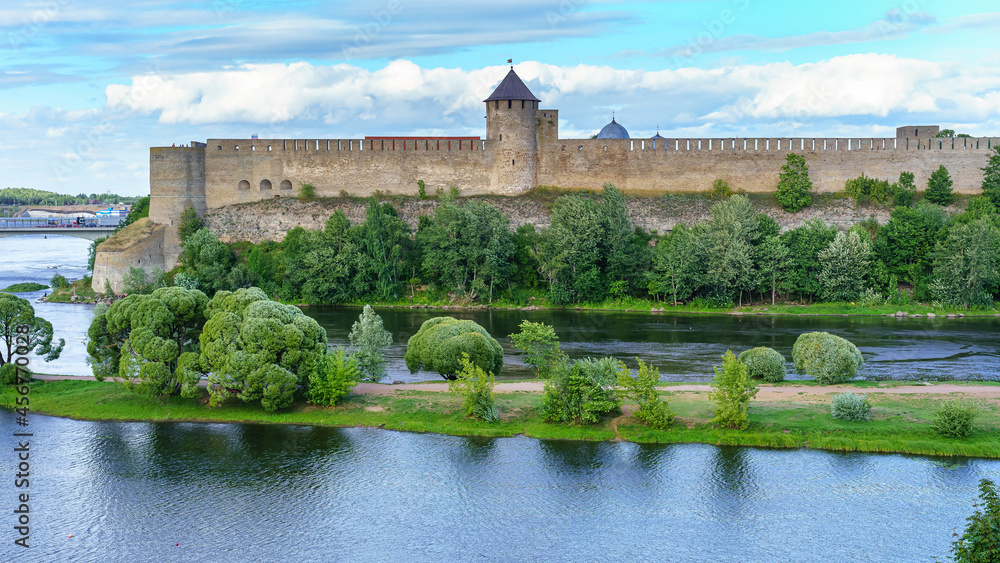Medieval castle by the river with a great defensive wall and stone towers.