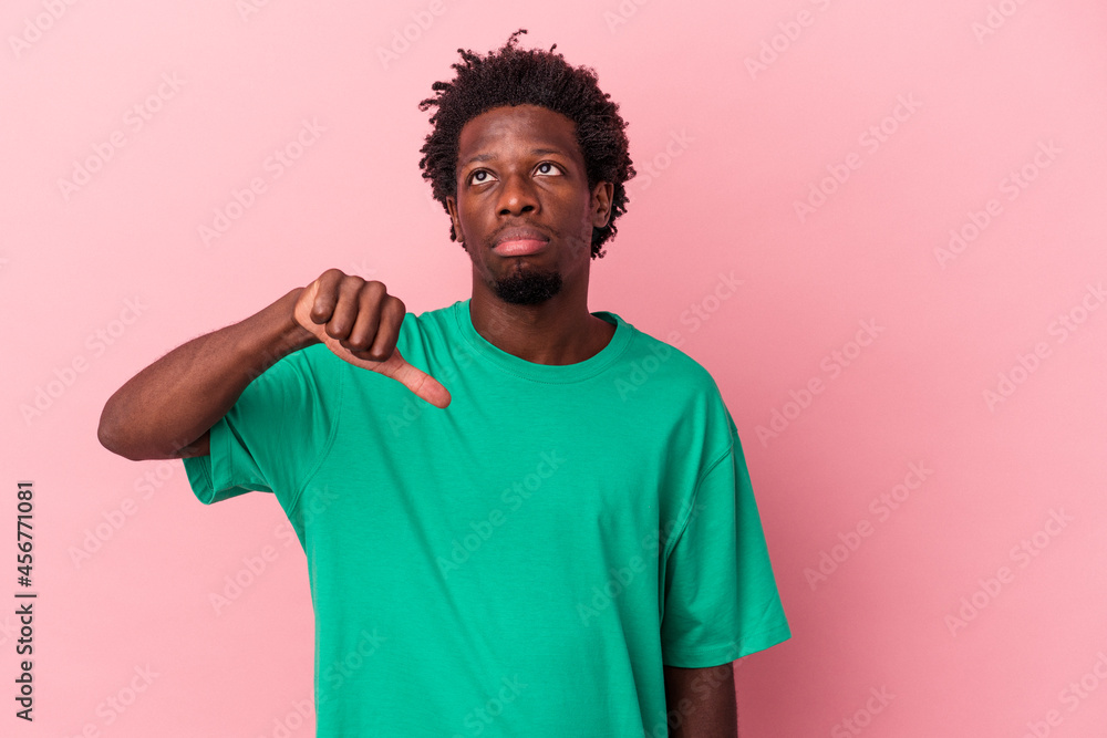Young african american man isolated on pink background showing a dislike gesture, thumbs down. Disagreement concept. Young african american man isolated on pink background showing a dislike gesture, thumbs down. Disagreement concept.