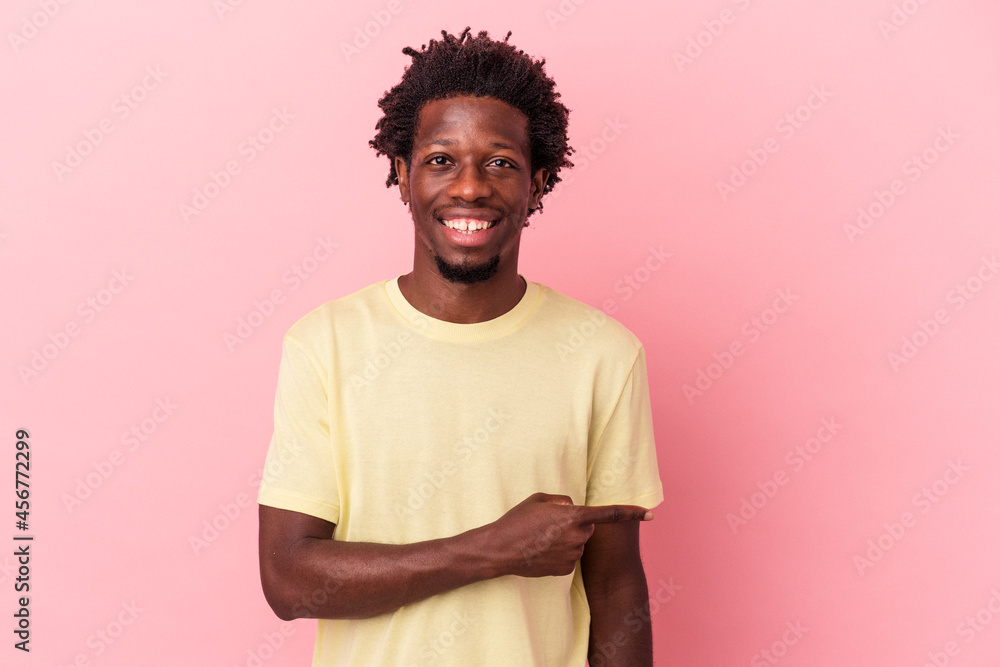 Young african american man isolated on pink background smiling and pointing aside, showing something at blank space. Young african american man isolated on pink background smiling and pointing aside, showing something at blank space.