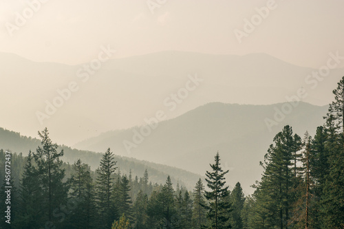 Smoky mountain landscape with mountain silhouette and light rays before sunset.