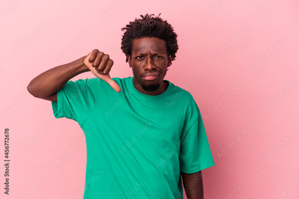 Young african american man isolated on pink background showing thumb down and expressing dislike. Young african american man isolated on pink background showing thumb down and expressing dislike.