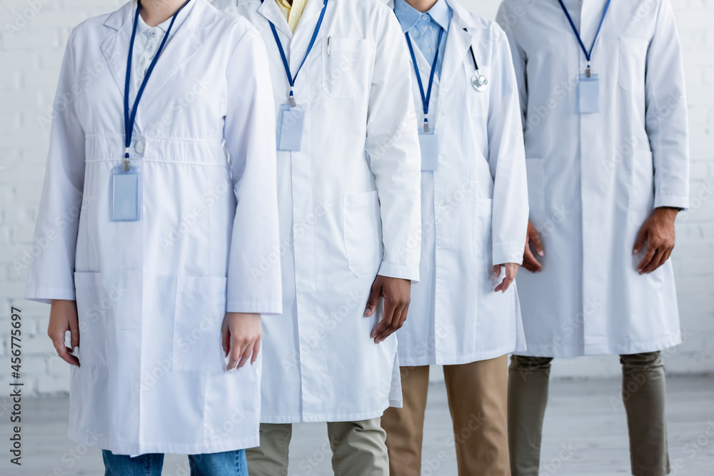 partial view of multiethnic doctors in white coats with name tags partial view of multiethnic doctors in white coats with name tags