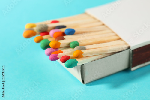 Matches with colorful heads in box on light blue background, closeup
