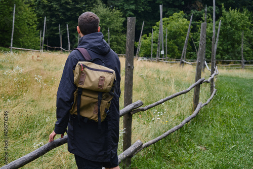 A man with a backpack walks through the countryside and enjoys the beautiful ethnic architecture. Outdoor adventure. Rest in the country. Travel and exploration. Healthy lifestyle