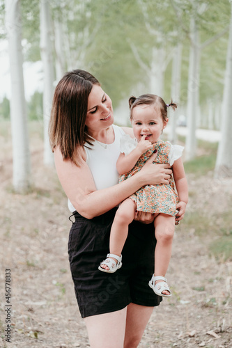portrait of beautiful mother holding baby girl in trees path. Family, fun and nature concept