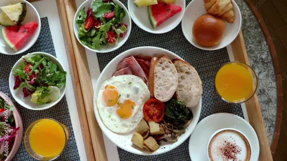 Room Service in Hotel - Top View of Two Trays Full of Food. Fresh Eggs, Green Salad, Bread, Fruits, Cups of Coffee and Orange Juice. Breakfast for Two. Vacation in Resort. Honeymoon Concept. Room Service in Hotel - Top View of Two Trays Full of Food. Fresh Eggs, Green Salad, Bread, Fruits, Cups of Coffee and Orange Juice. Breakfast for Two. Vacation in Resort. Honeymoon Concept.