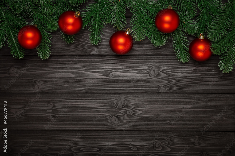 A beautiful garland of green fir branches and red Christmas balls on a dark wooden background. Side view. Perfect retouching. Advertising, banner, layout for design. Copy space. A beautiful garland of green fir branches and red Christmas balls on a dark wooden background. Side view. Perfect retouching. Advertising, banner, layout for design. Copy space.