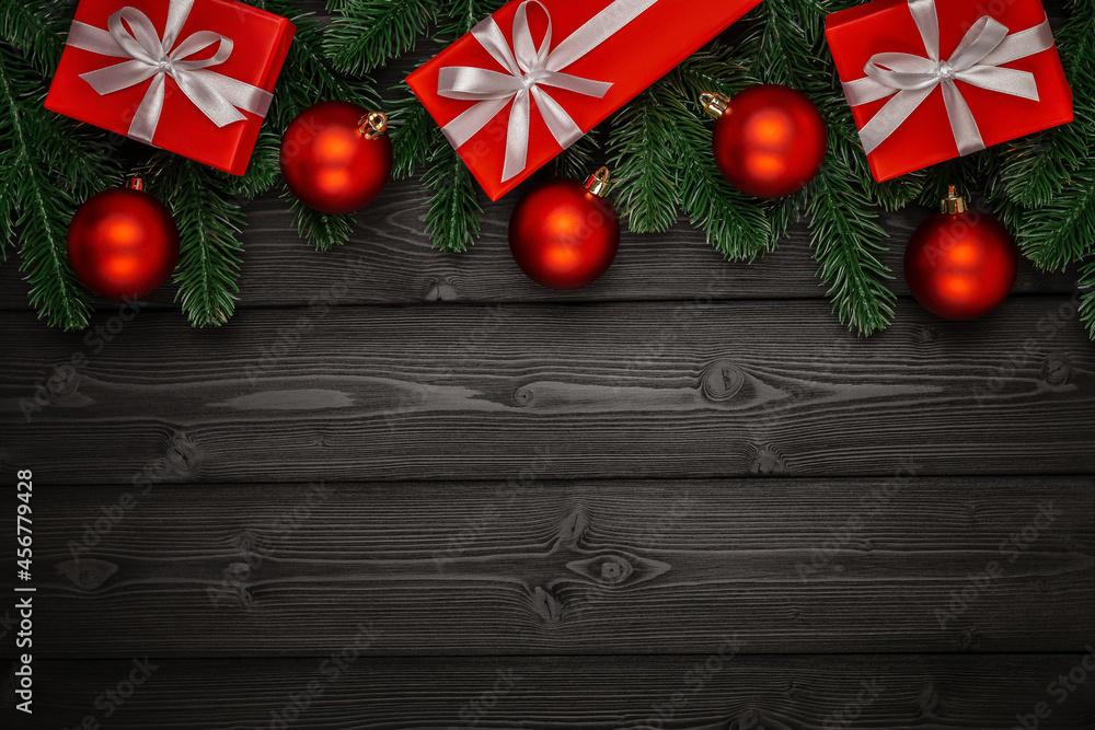 A garland of green fir branches, red Christmas balls and gift boxes with white satin bows on a dark wooden background. Side view. Perfect retouching. Advertising, banner, layout for design. Copy space A garland of green fir branches, red Christmas balls and gift boxes with white satin bows on a dark wooden background. Side view. Perfect retouching. Advertising, banner, layout for design. Copy space