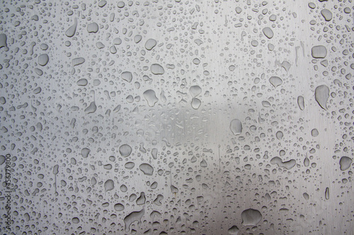 Abstract art texture background of raindrops on shiny brushed stainless steel metal surface of old retro vintage car. Drops of rainwater on a piece of polished industrial equipment