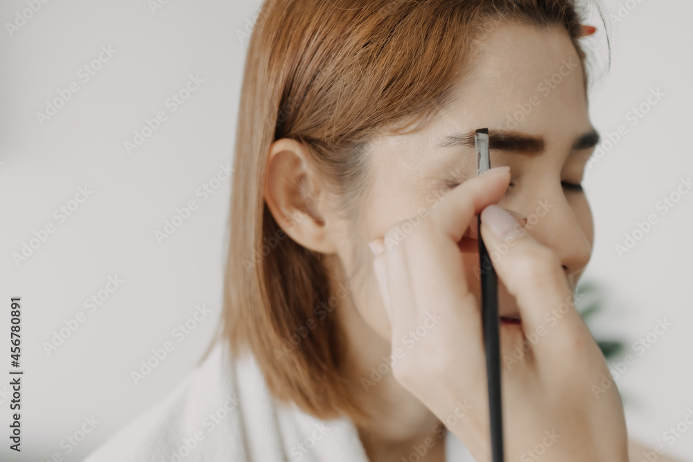 Asian woman makeup artist is at work and wearing makeup on her model.