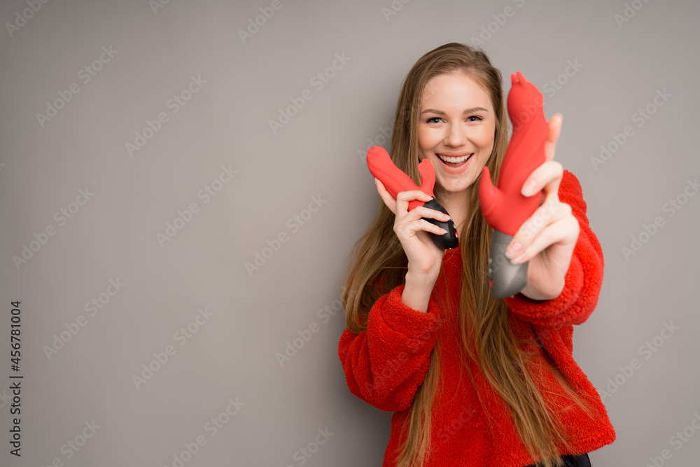 An attractive girl of European appearance in a red sweater happily holds a red phallus An attractive girl of European appearance in a red sweater happily holds a red phallus