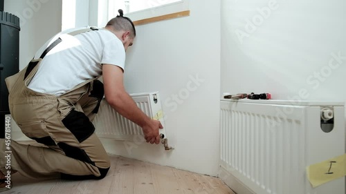 Plumber installing new steel hot water central heating radiator