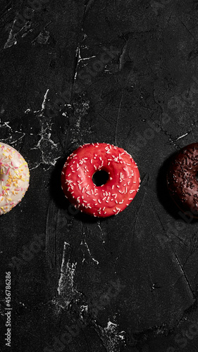 Donuts Set on Black. Different type of donuts: with chocolate, pink glaze and sprinkles. Top view.