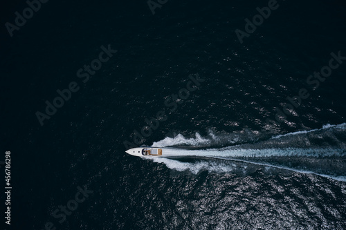 Speed boat faster movement on the water top view. Speedboat movement on the water. Large white boat driving on dark water. Speedboat on dark blue water aerial view.