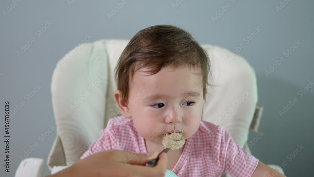 Cute Toddler Girl Eating Oatmeal Seated In High Chair At Home. Closeup Cute Toddler Girl Eating Oatmeal Seated In High Chair At Home. Closeup