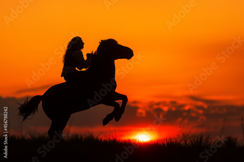 silhouette of a woman on a rearing horse against the sunset