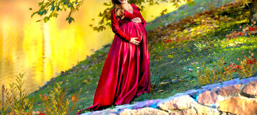 Fototapeta premium Banner with a pregnant woman. Maternity concept. The background is a lake in autumn, beauty and naturalness. Copy space