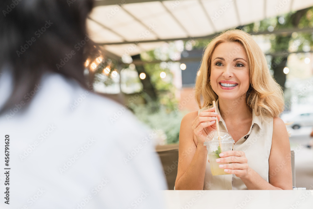 Friendship concept. Two female best friends women sisters visiting cafe, drinking cocktails lemonade together, talking, sharing news, gossiping outdoors. Friendship concept. Two female best friends women sisters visiting cafe, drinking cocktails lemonade together, talking, sharing news, gossiping outdoors.