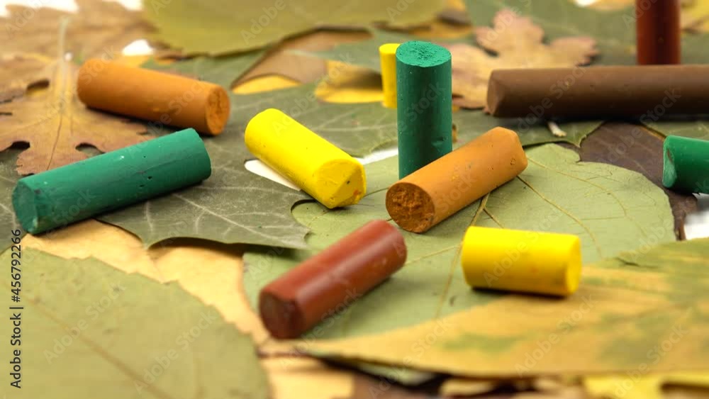 Yellow, green and brown wax crayons lie on colorful autumn leaves, background. Natural materials for creativity and painting lie on a table. Yellow, green and brown wax crayons lie on colorful autumn leaves, background. Natural materials for creativity and painting lie on a table.