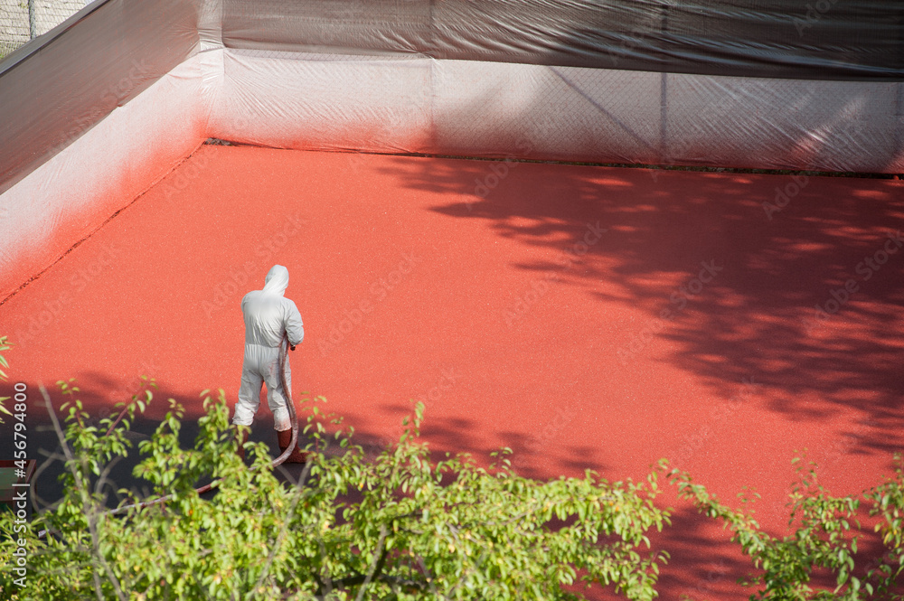 Liquid rubber coating process. A worker dressing security suit spraying
