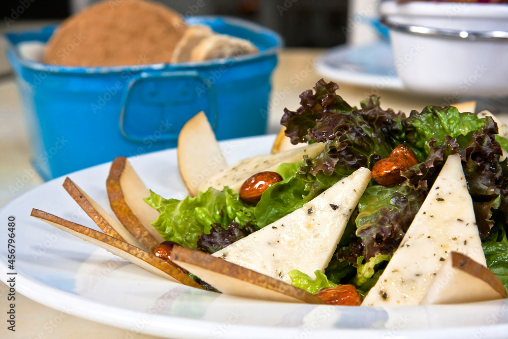 Sliced pear salad with cheese and caramelized almonds, fresh green salad on restaurant table Sliced pear salad with cheese and caramelized almonds, fresh green salad on restaurant table