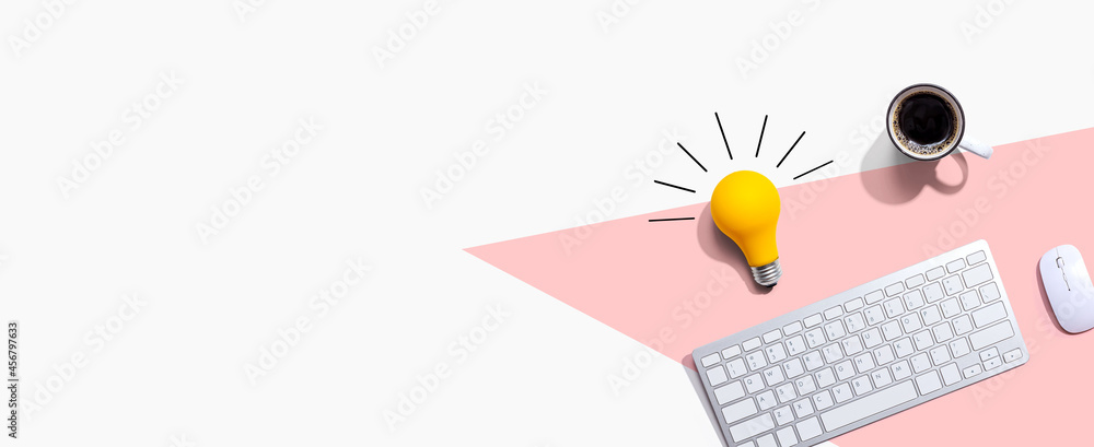 Computer keyboard with a yellow light bulb from above Computer keyboard with a yellow light bulb from above